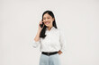 © Illhamt - An Asian woman smiles while holding a phone, exuding confidence. Captured in a bright studio, this image aims to represent connectivity and modern lifestyle choices.