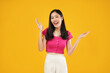 © Illhamt - Photo of excited and surprised young asian woman saying wow with amazement, raising hands up near face, standing against yellow background