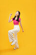 © Illhamt - full-body portrait of an Asian woman who is happy and smiling on a yellow background