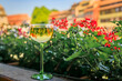 A glass of Gewurztraminer wine at an outdoor restaurant, blurred half timbered houses and flowers in the Petite France district of Strasbourg, France