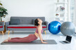 © Nopphon - Beautiful smiling Female wearing sportswear exercise training yoga in living room. Attractive asian young fitness woman stretching body warming up before workout at home.