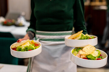 Wall Mural - Men's waiter hands hold a Caesar salad with croutons, cheese, eggs, tomatoes and grilled chicken