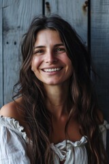 Wall Mural - A woman with long brown hair smiling at the camera. Suitable for various uses