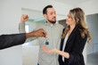 © ABCreative - Happy bearded guy raising his fist as his thrilled adorable and gorgeous wife accepts the keys from the realtor.