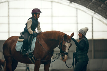 Female instructor teaching little girl, child horseback rising. Kid practicing trail riding, dressage. Concept of sport, childhood, school, course, active lifestyle, hobby