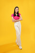 © Illhamt - full-body portrait of an Asian woman who is happy and smiling on a yellow background