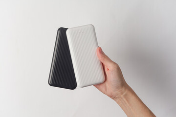 Hands holding white and black external battery power banks on white background