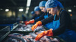 Group of seafood processing staff working with fresh sardines in plant