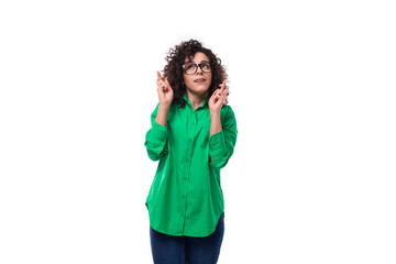 Wall Mural - brunette young caucasian lady with curly hair dressed in a green shirt is waiting for the fulfillment of a wish