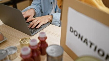 Wall Mural - Serious yet relaxed, man volunteer at work, hands locked on laptop, sitting at a table in charity center, offering online support with crucial donation services