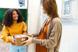 © Dasha Petrenko - Woman opening house entrance door while meeting courier with online order, postwoman delivering package to customer
