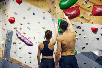 Wall Mural - Young man and woman, athletes looking on climbing wall, discussing training techniques. Bouldering school. Concept of sport, bouldering, sport climbing, hobby, active lifestyle, training course