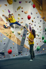 Wall Mural - Woman, bouldering trainer teaching child little girl bouldering activity, techniques. Little girl climbing wall, indoor class. Concept of sport climbing, hobby, active lifestyle, school