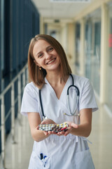 Wall Mural - Bunch of pills in hands. Female doctor in white coat is in the hall