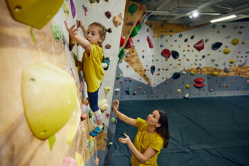 Wall Mural - Little girl, child training with instructor, practicing bouldering activity, techniques. Little girl climbing wall, indoor class. Concept of sport climbing, hobby, active lifestyle, school, course