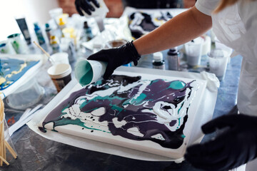 Master class on an Acrylic Fluid Pouring. Young women paint with liquid acrylic in an art workshop