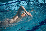 Fototapeta Łazienka - Professional athlete. Young man, swimming sportsman in motion, wearing cap and goggles swimming in pool. Concept of pool sports, water sport, competition, active lifestyle