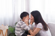 © Rakchanok - Happy family Asian mother and son playing together touching cheeks each other laughing out loud kidding with fun indoor at home weekend holiday, mom and kid bonding relationship, motherhood tenderness