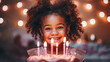 Cute African 6 year old curly girl in a pink dress smiles at her birthday party. A girl stands next to a cake with burning candles. Festive dessert. Garland in blur. Children's birthday concept