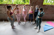 This image captures a moment of adaptation and resilience, showing a group of women in a workout setting during times that may require health precautions. They stand in a circle, wearing protective
