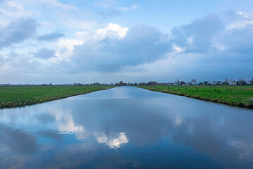 Wall Mural - serene image of clouds over a wide ditch in the dutch polder landscape