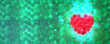 Heart made up of small shiny red spheres on green spheres background