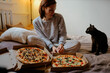© velimir - lonely woman at home with a cat ordered two pizzas. Eating pizza in bed at home.