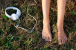 Bare female feet  on a grass and headphones