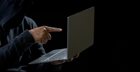 Hand hacker spy man one person in black hoodie sitting on table looking computer laptop used login password attack security to data digital internet network system night dark background copy space