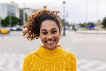 Joyful latin american student girl smiling at camera outdoors. Portrait of happy young multiracial woman over urban background