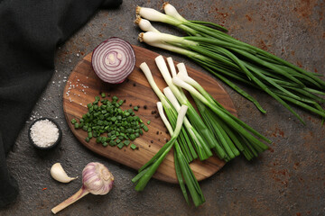 Sticker - Board with slices of fresh scallion and onion on dark background