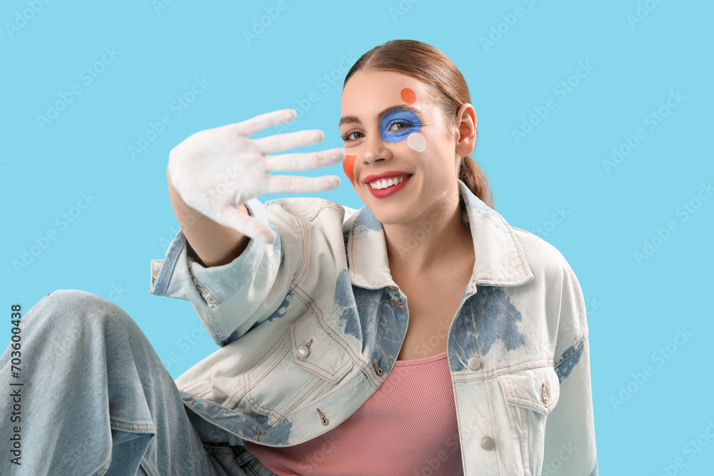 Young woman with painted face on blue background