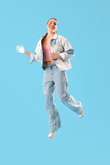 Wall Mural - Young woman with painted face jumping on blue background