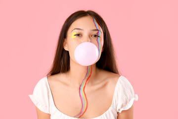 Wall Mural - Young Asian woman with painted face chewing gum on pink background, closeup