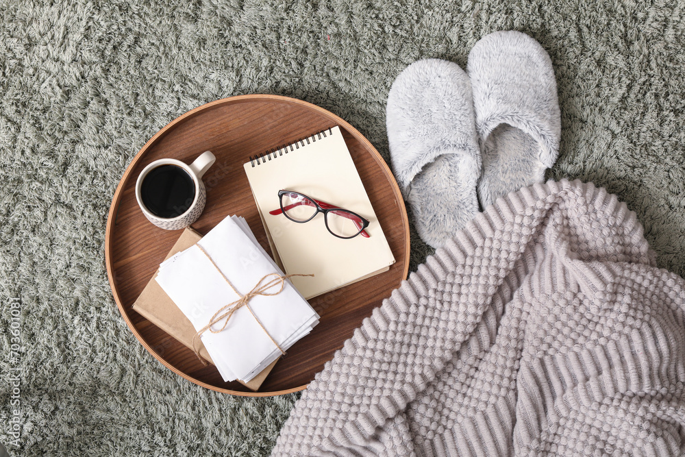 Soft slippers with with coffee cup, letters and plaid on green carpet, top view
