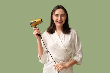 Wall Mural - Beautiful young woman with hair dryer on green background