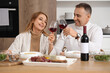 © Pixel-Shot - Mature couple with glasses of wine having dinner in kitchen