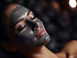 Closeup of a woman's face applying a charcoal detox facial mask relaxing with spa 