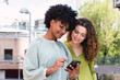© BUDDHA - Reaching out to new networks. Shot of two businesswomen looking at something on a cellphone in the city.