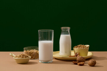 Wall Mural - Over the dark background, a bottle and glass of milk are arranged with few walnuts and soybeans. Research shows that making nuts a regular part of a healthy diet
