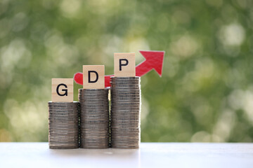 GDP word on coins money and red arrow on natural green background, GDP (Gross Domestic Product) concept