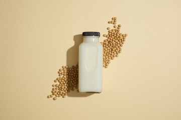 Wall Mural - A bottle filled with milk decorated over beige background with a lot of soybeans. Soybean (Glycine max) can be found in traditional foods, snacks, and daily necessities