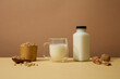 A glass and unlabeled bottle filled with milk are displayed with soybeans and walnuts. Soy drink is one of the easiest and most convenient choices
