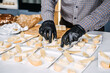 Caterer Preparing Cheese Platters for an Event. Professional caterer arranges various types of cheese on plates, wearing gloves for hygiene while preparing for a gourmet event.
