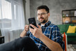 © Miljan Živković - Adult man use mobile phone smartphone at home browse internet or send text messages sms texting