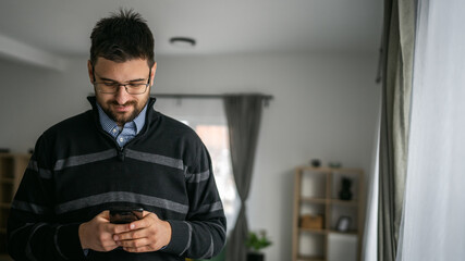 Adult man use mobile phone smartphone at home browse internet or send text messages sms texting