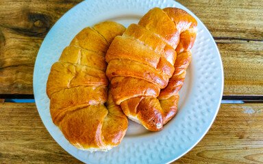 2 croissants on a white plate on a wooden table in Mexico.