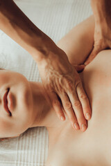 Wall Mural - Hands of female chiropractor massaging shoulders of young woman lying on massage table. Concept of physical therapy treatment ,neck pressure point