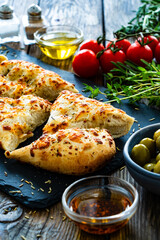 Poster - Focaccia alle olive - baked sandwich with green olives and rosemary on wooden background
