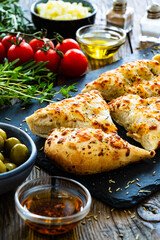 Wall Mural - Focaccia alle olive - baked sandwich with green olives and rosemary on wooden background
